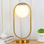 Lampe globe opalin dans un anneau, doré ou noir – Lugano allumée