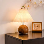 Lampe abat-jour plissé et pied boule en bois – Conques allumée