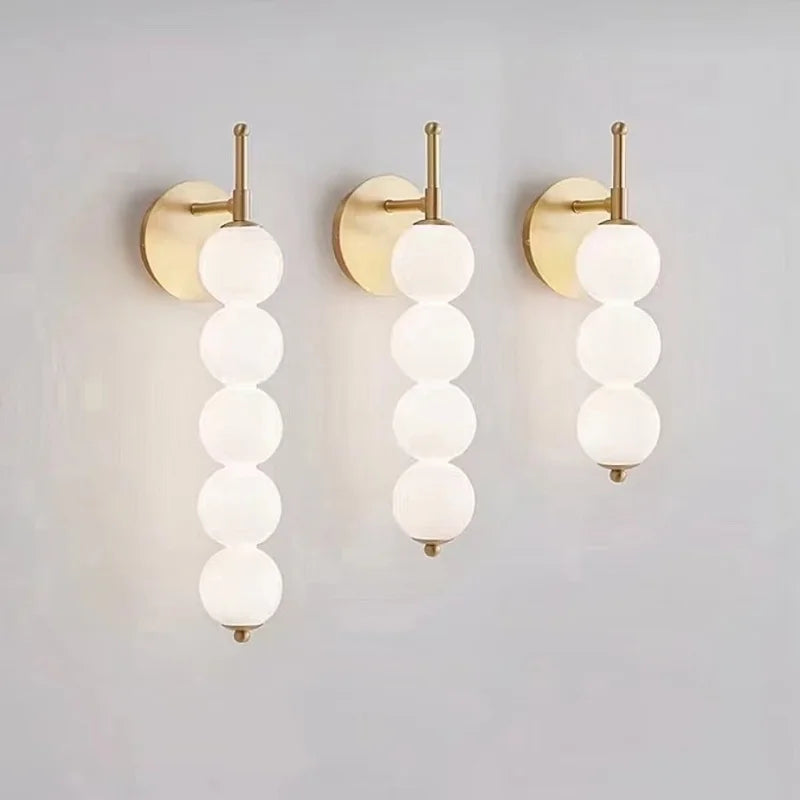 Applique colonne de globes opalins, dorée ou noire – Pézenas allumée